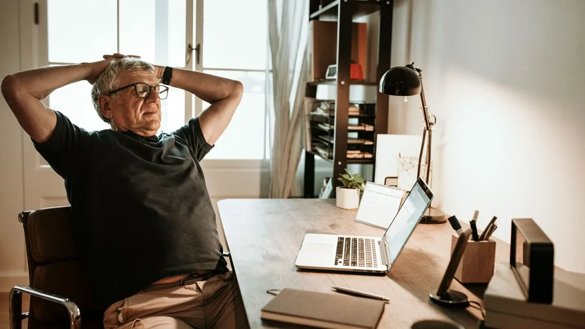 Rentner sitzt vor einem Laptop und denkt über die Aktivrente nach.