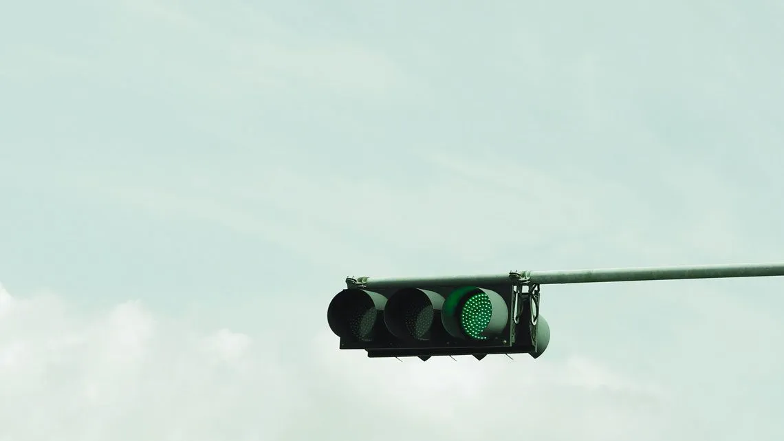Nahaufnahme einer Ampel vor hellem Himmel, die auf Grün geschaltet ist