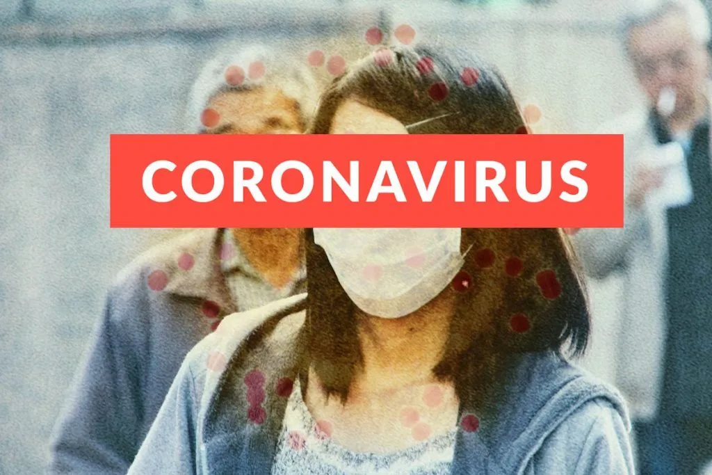 Frau mit Mundschutz vor rotem Banner „Coronavirus“, im Hintergrund weitere Personen mit Masken