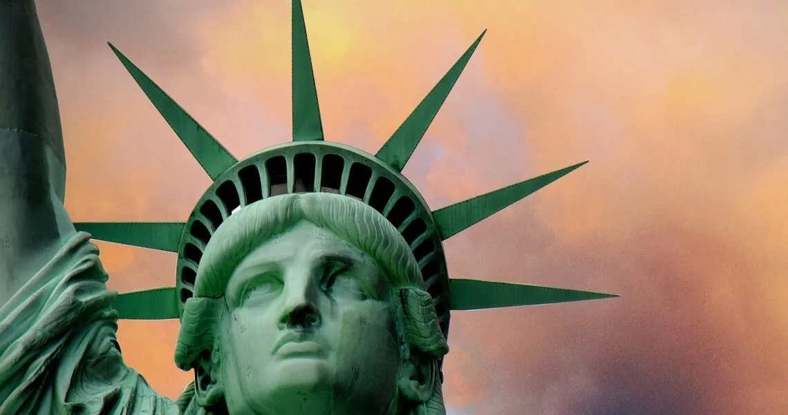 Nahaufnahme der Krone der Freiheitsstatue vor orange-violettem Abendhimmel