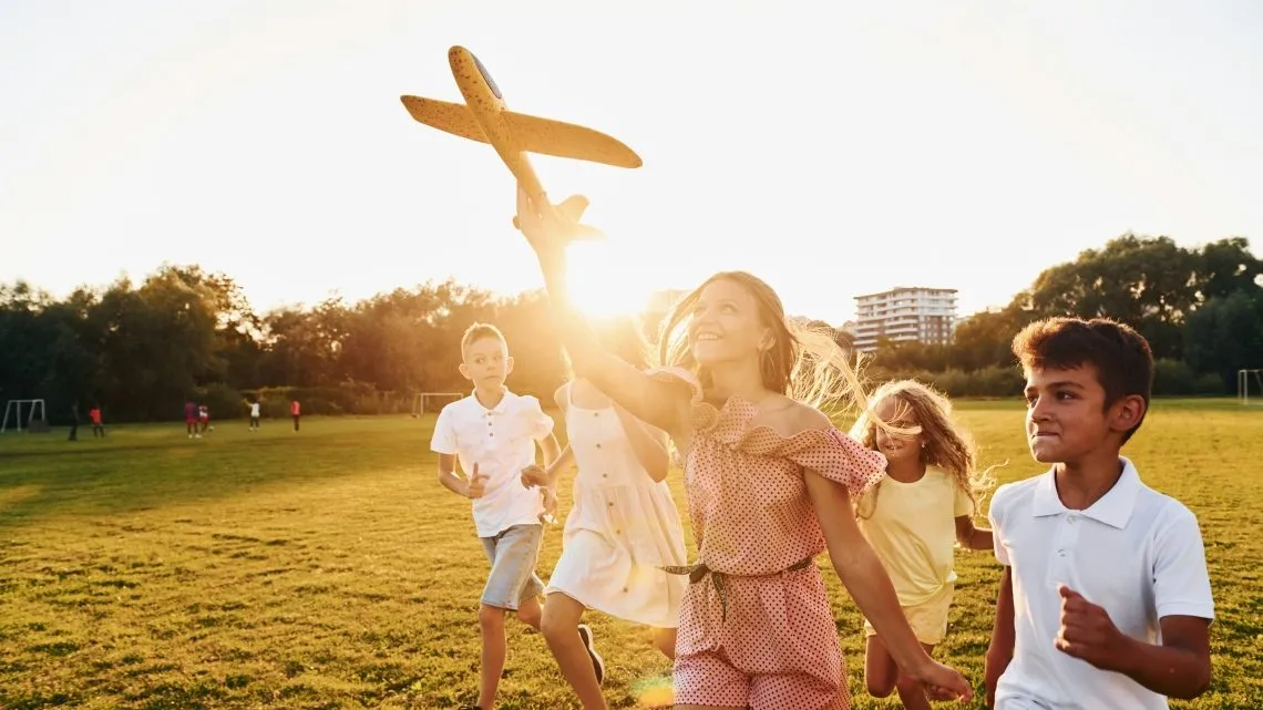 Kinder auf einer Wiese, die ein Spielzeug-Flugzeug starten lassen – als Symbolbild für die Frühstart-Rente.