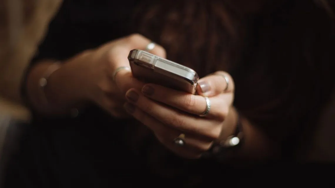 Frau hält Handy um PSD2 Richtline nachzukommen