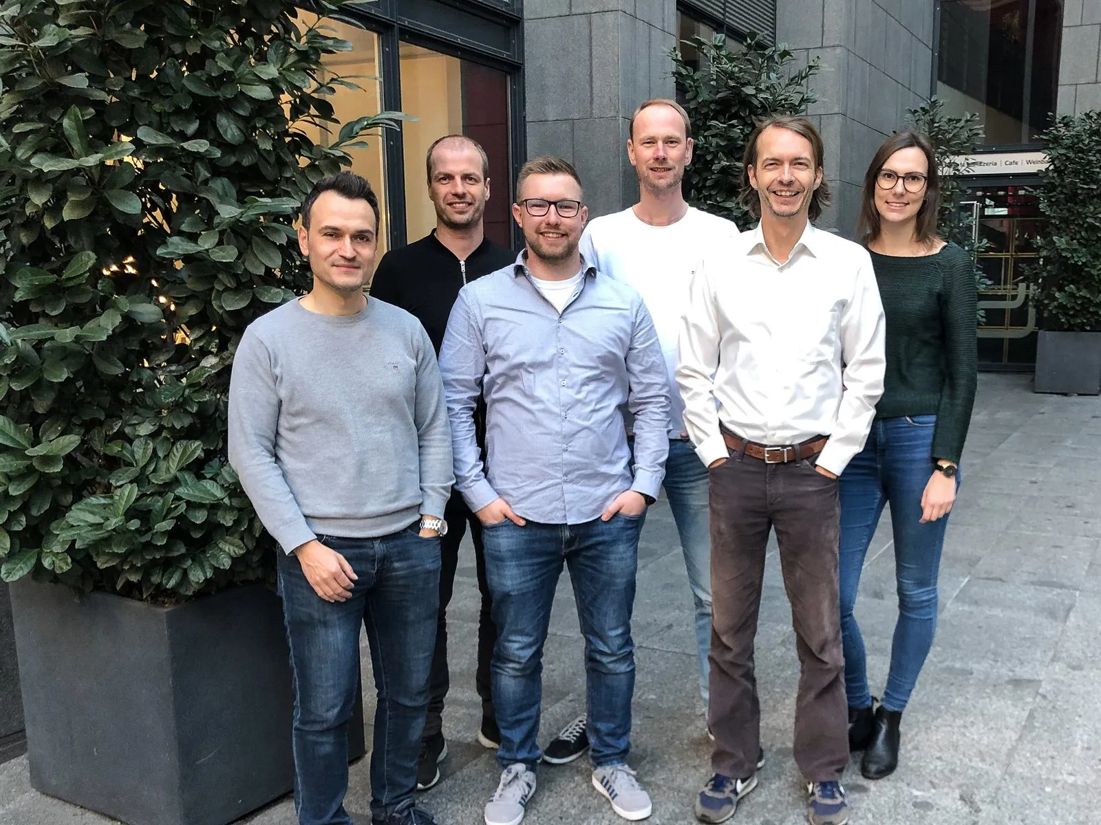 Mehrere Personen aus dem EVERGREEN-Team stehen lächelnd vor einem Gebäude im Freien