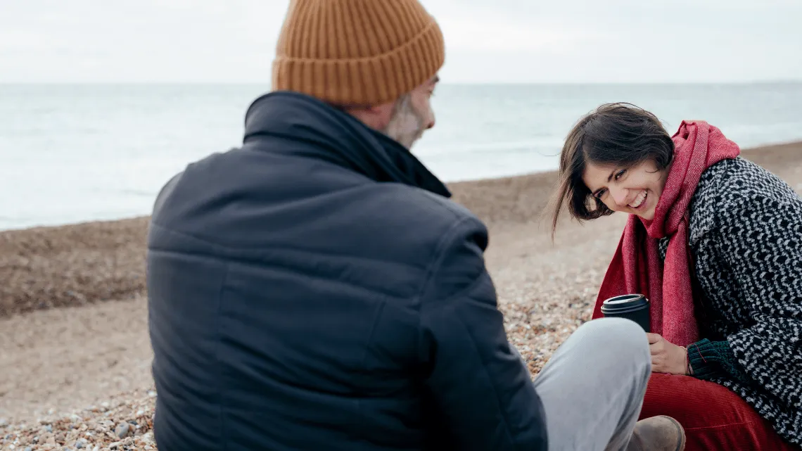 Zwei Menschen unterhalten sich am Strand über ihre Neujahrsvorsätze
