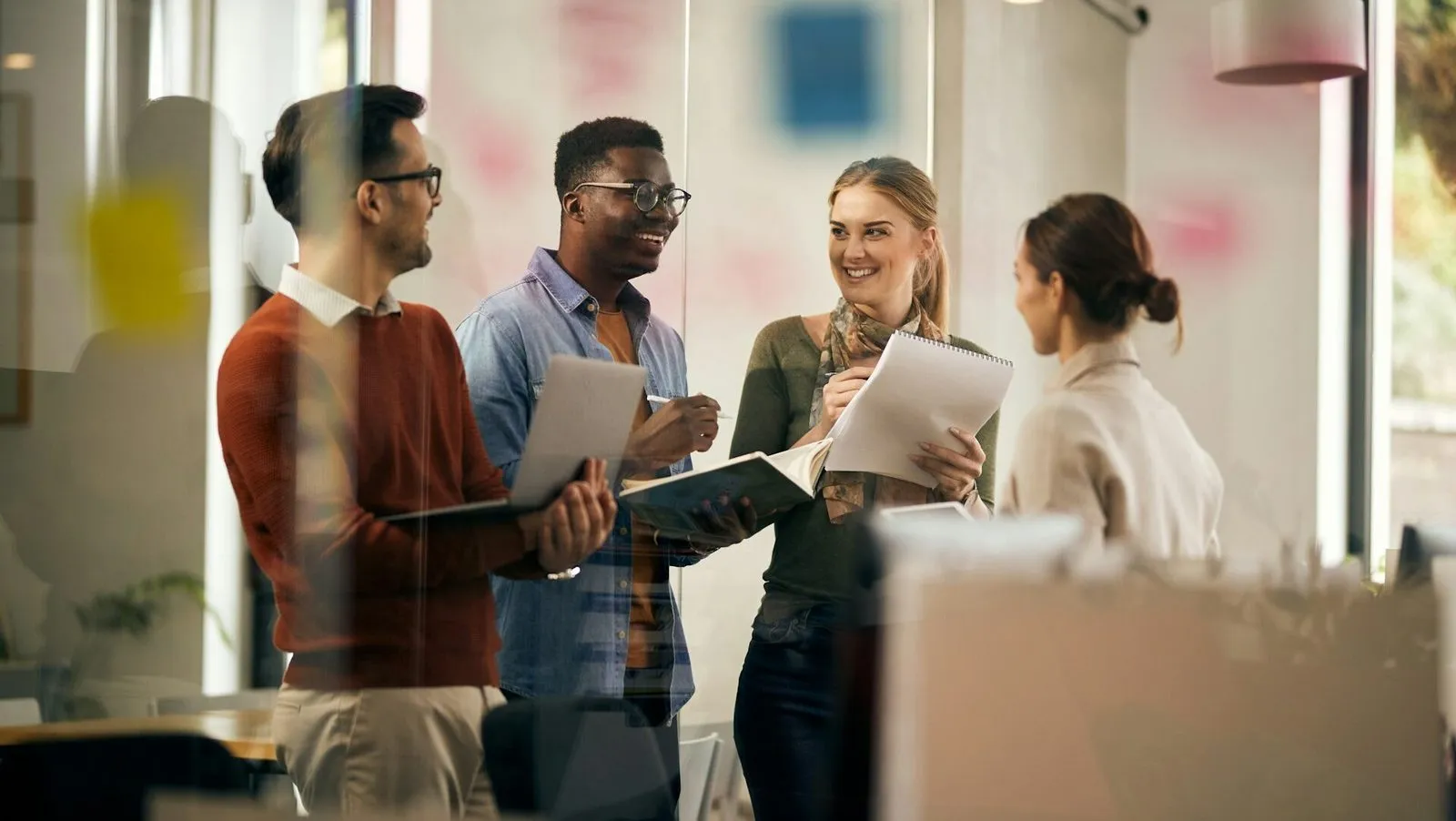 Fröhliches Team spricht stehend miteinander im Büro.