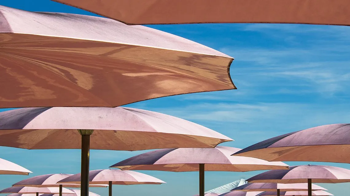 Reihen bunter Sonnenschirme vor blauem Himmel, mehrere Schichten übereinander gestaffelt